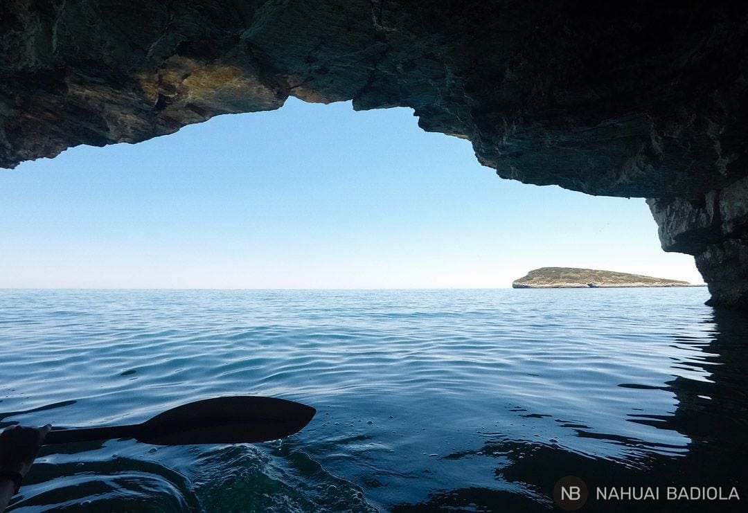 Kayaking out of a cave overlooking the island of Campi, Gargano.